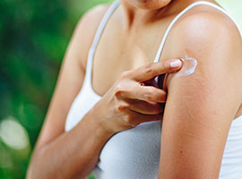 Una joven aplicando una loción para la comezón en una picadura de mosquito en el brazo.
