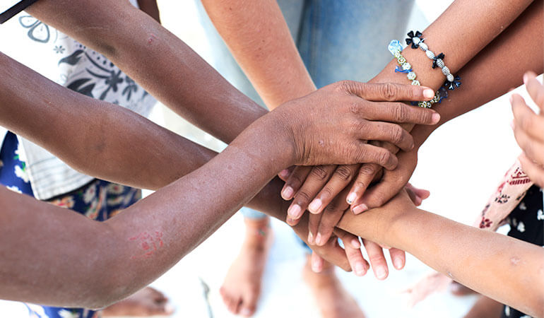 Una vista superior de un grupo de personas multiétnicas tomadas de la mano.